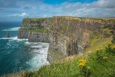 Scenic view of cliff by sea against sky