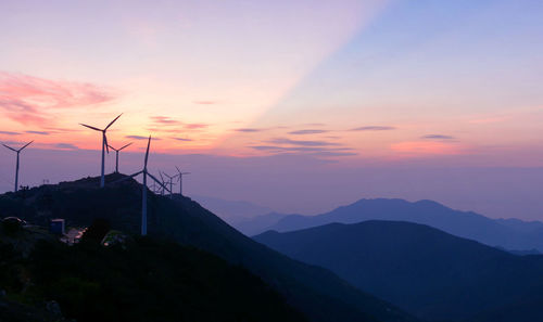 Windmills on mountain against sky during sunset