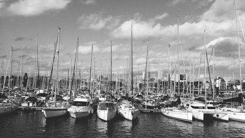Boats moored at harbor in city against sky