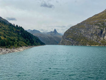 Scenic view of sea by mountains against sky