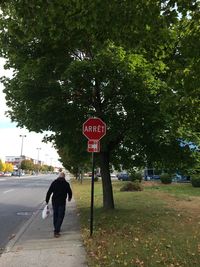 Rear view of man crossing sign on road