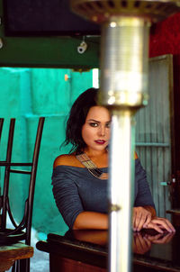 Portrait of young woman sitting by table