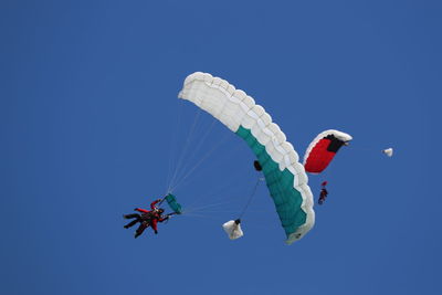 Low angle view of man paragliding against clear blue sky