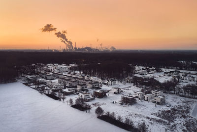 Drone image of a residential area covered with snow and industrial factory during sunset in germany