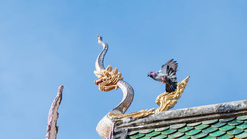 Low angle view of angel statue against clear blue sky