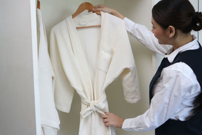 Midsection of woman holding white dress