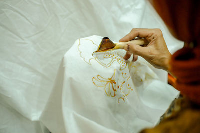 Cropped hand of woman drawing on textile