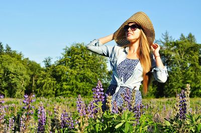 Woman wearing hat standing on field against sky