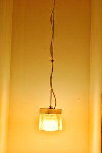 Close-up of illuminated electric lamp hanging by wall