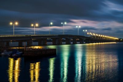 Illuminated bridge over river against sky at night