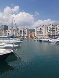 Sailboats moored in harbor against buildings in city