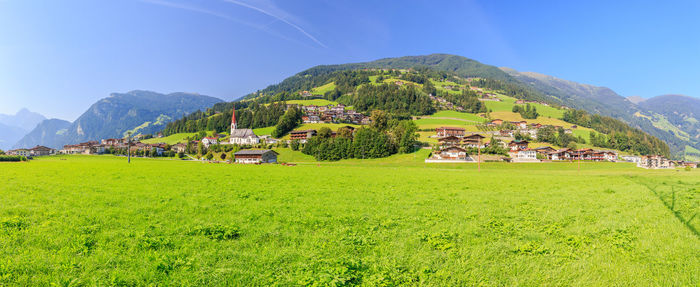 Scenic view of field and houses against sky