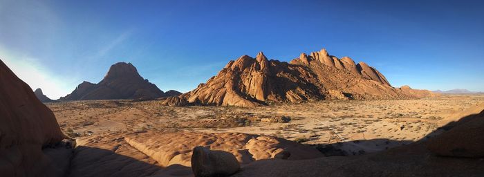 Panoramic view of rocky mountains against blue sky