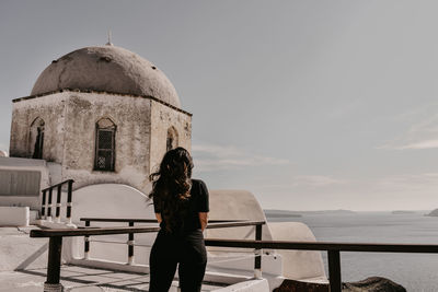 Rear view of woman standing by railing against sky