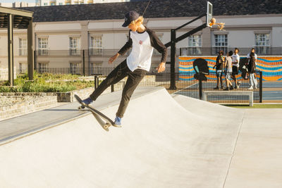 Full length of man jumping skateboarding against building