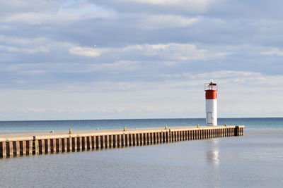 Lighthouse by sea against sky