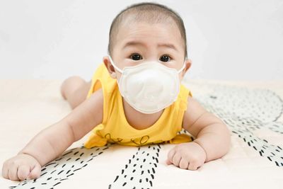 Little baby in medical mask lying on bed at home.concept covid-19 coronavirus pandemic. 