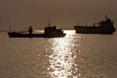 Silhouette ship in sea against sky during sunset