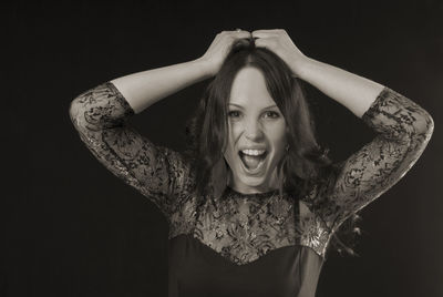 Portrait of young woman shouting against black background