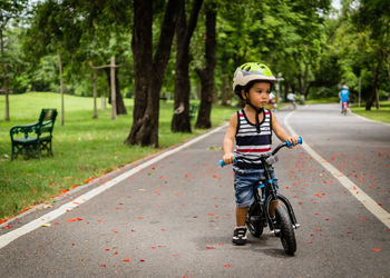 Full length of cute boy standing with bicycle on road