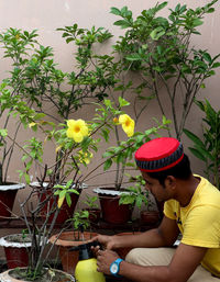 Side view of young man holding potted plant