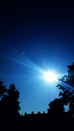 Low angle view of silhouette trees against blue sky
