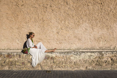 Woman sitting against a wall and smiling