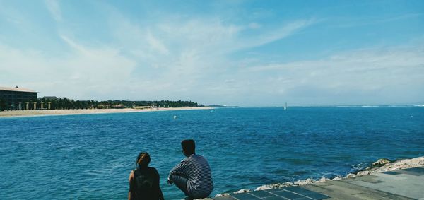 Rear view of people looking at sea against sky