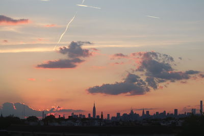 Silhouette of city against cloudy sky during sunset