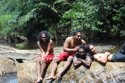 Happy men on rock in forest