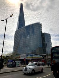 Cars on road by buildings against sky