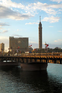View of buildings at waterfront against cloudy sky