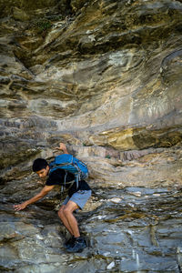 Young boy climbing the rocks wearing a backpack.