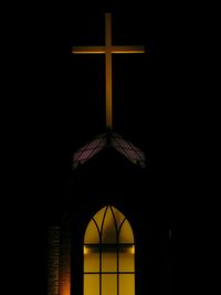 Low angle view of cross on building at night