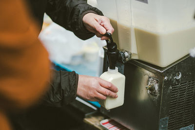 Close-up of man filling drink in bottle