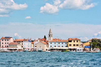 Buildings at waterfront against cloudy sky