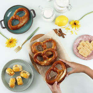 Snacking time with hand, pretzel, biscuit, and pastry roll with melted cheese . 