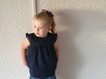 Cute girl standing against wall at home