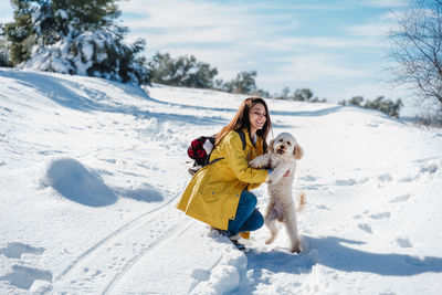 Woman with dog on snowcapped mountain against sky