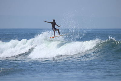 Man surfing in sea against sky