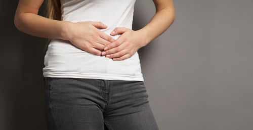 Midsection of woman standing against black background
