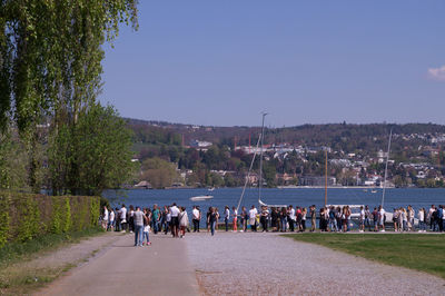 People walking by plants against clear sky