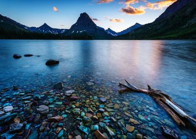 Scenic view of lake by mountains against sky during sunset