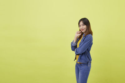 Portrait of a smiling young woman against yellow background