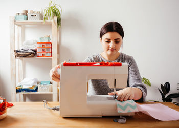 Young woman using sewing machine at home