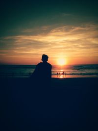 Silhouette man on beach against sky during sunset