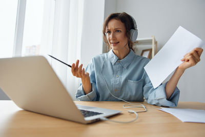 Portrait of young businesswoman using laptop at table