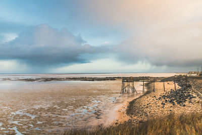 Scenic view of fishing hut and sea against sky