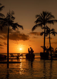 Silhouette people at beach against sky during sunset