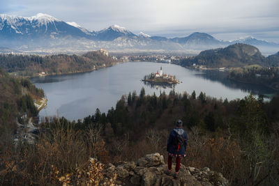 Rear view of woman looking at lake while standing on mountain